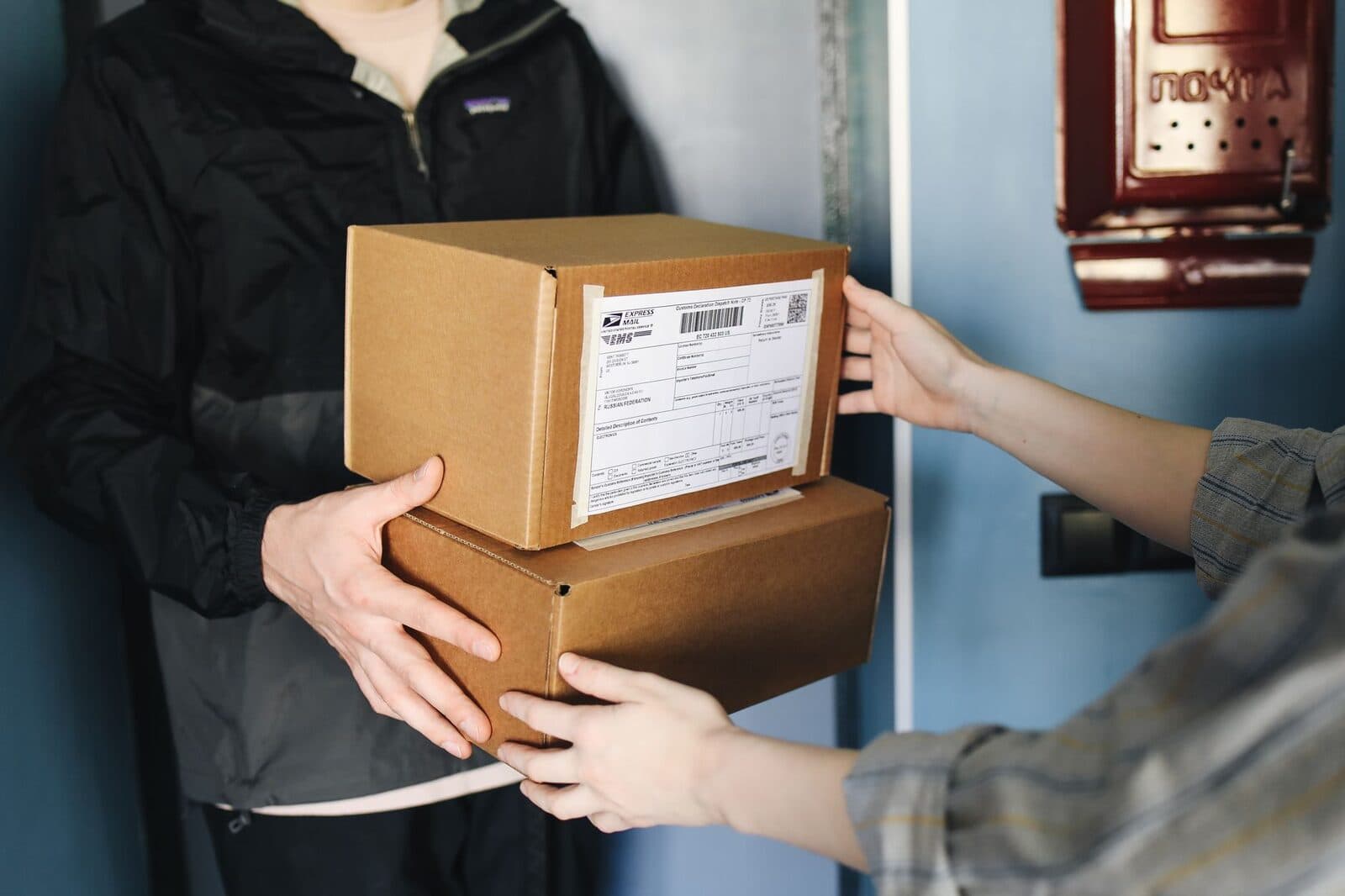 Close-up of hands exchanging cardboard boxes indoors, symbolizing delivery service.