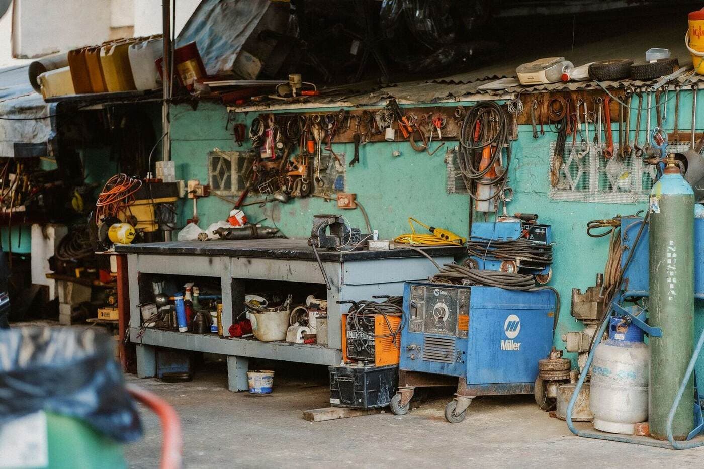 A cluttered workshop with tools, welding equipment, and storage solutions.